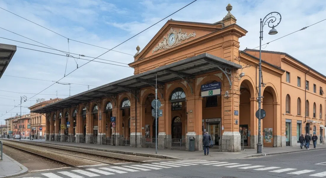 la salida de Via de' Carracci desde Bologna Centrale hacia Bolognina, con los accesos ferroviarios y los bloques residenciales bajos justo más allá de la estación