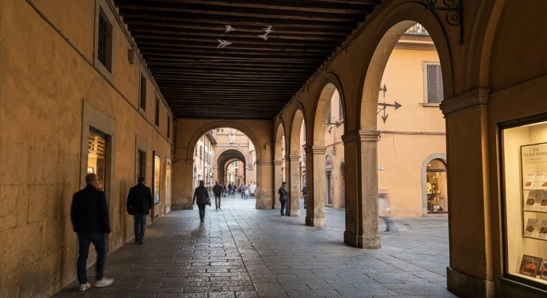 el pasaje interior de Corte Isolani mirando hacia Strada Maggiore, con las vigas del pórtico de roble del siglo XIII y las tres flechas visibles sobre la cabeza